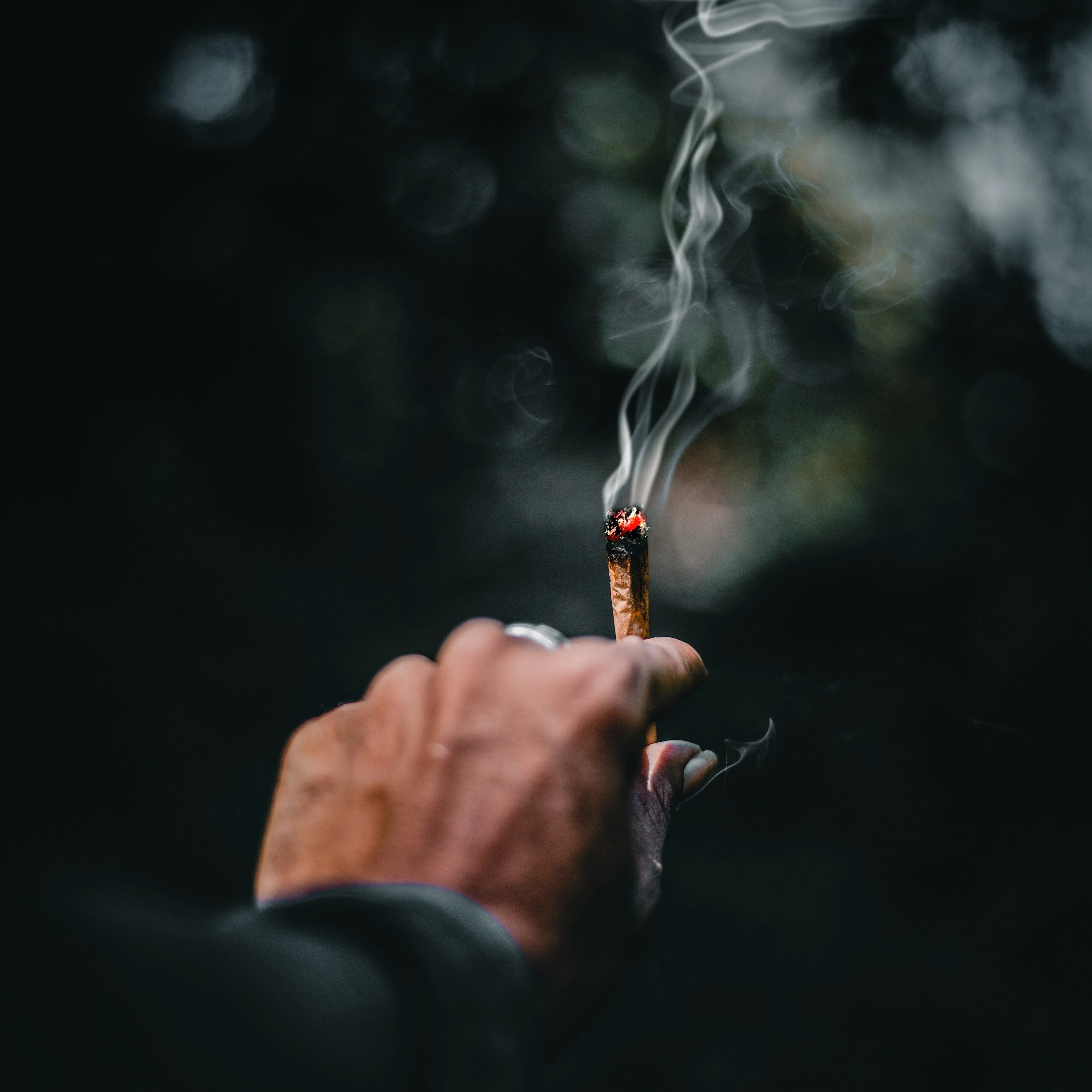 Homme qui tient un joint dans ses mains en train de le fumer, chill, smoker