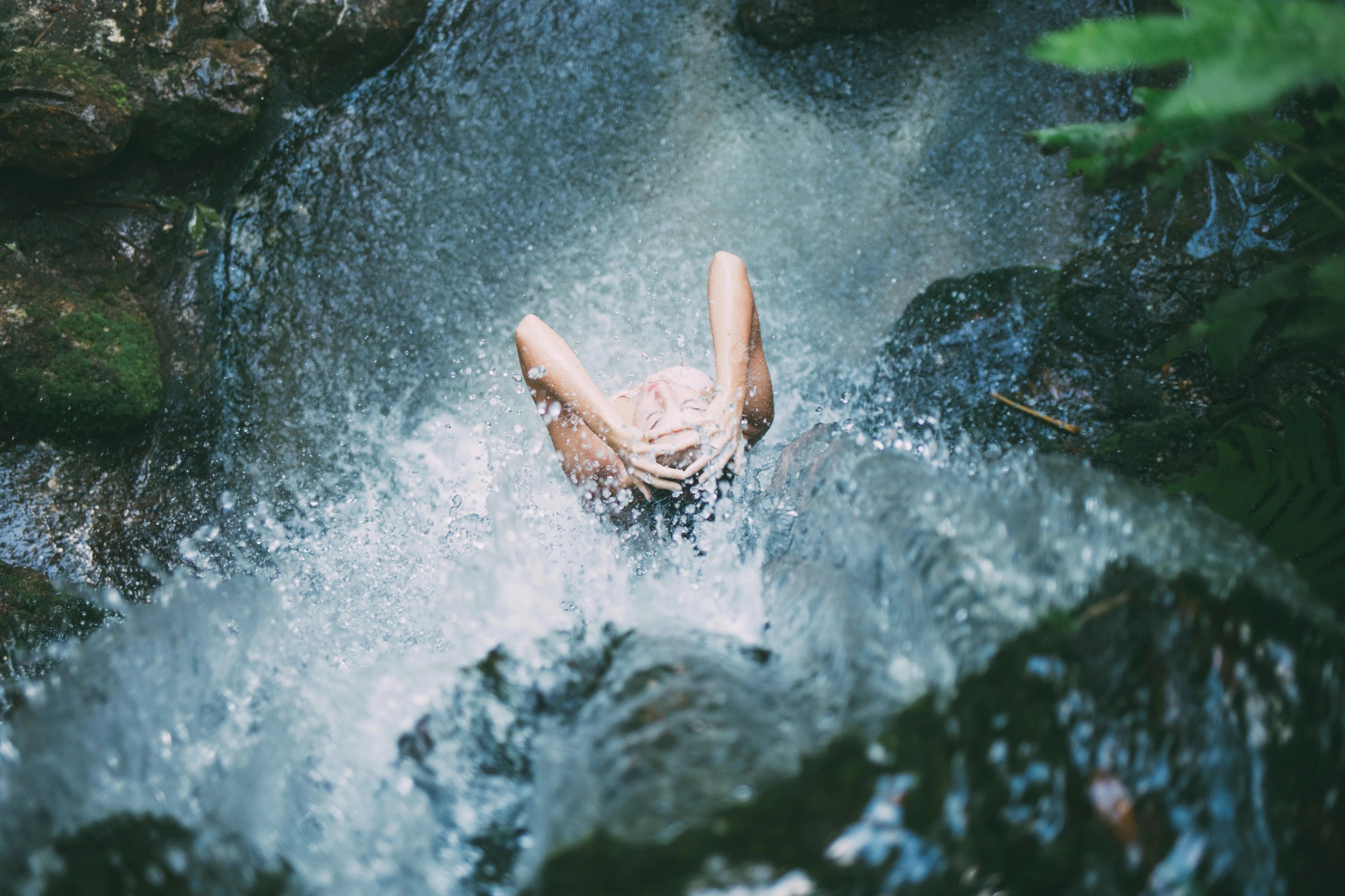 Femme qui se lave les cheveux sous une cascade d'eau dans une rivière, nature, relax, bio bien-être