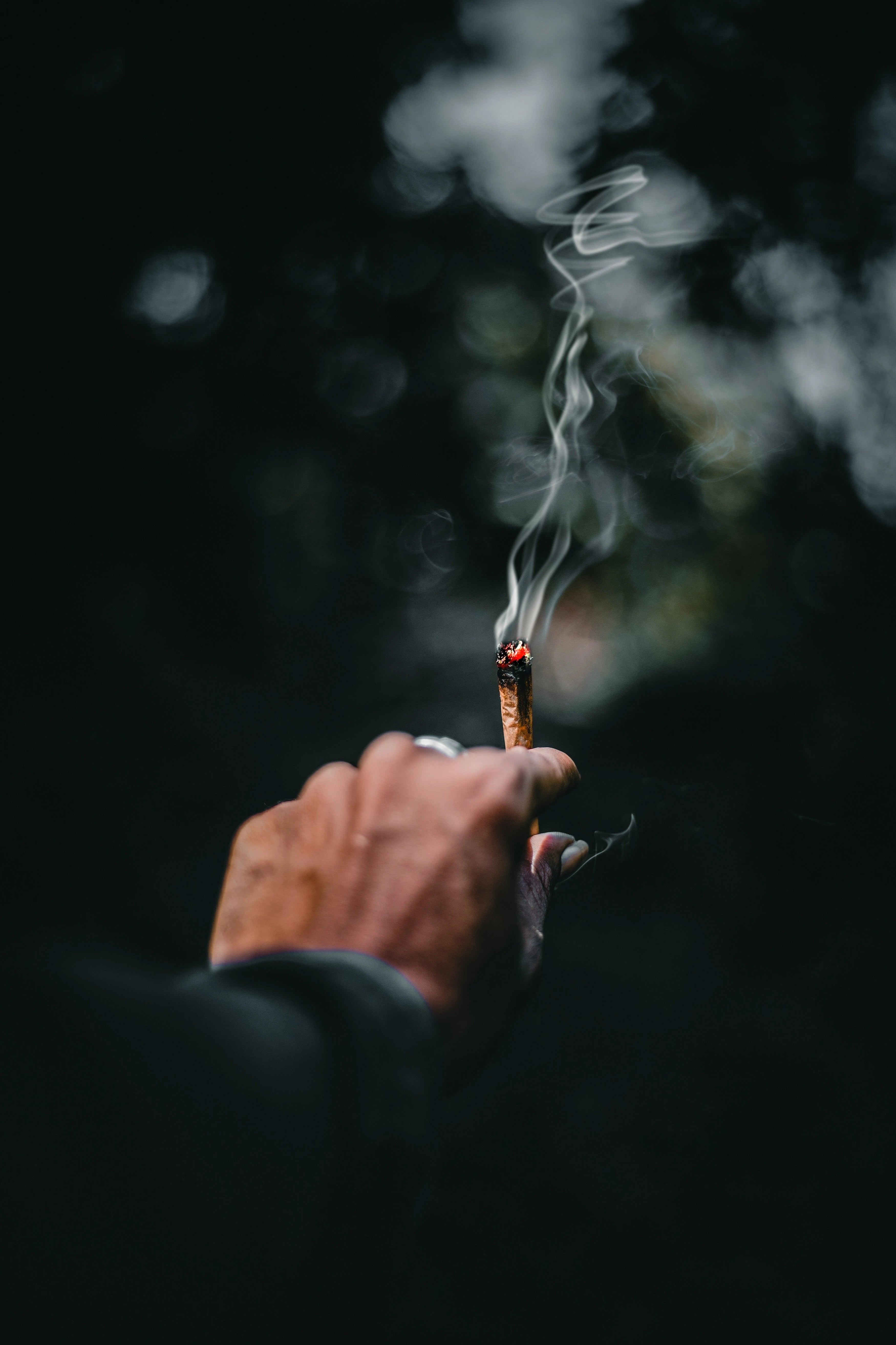 Homme qui tient un joint dans ses mains en train de le fumer, chill, smoker